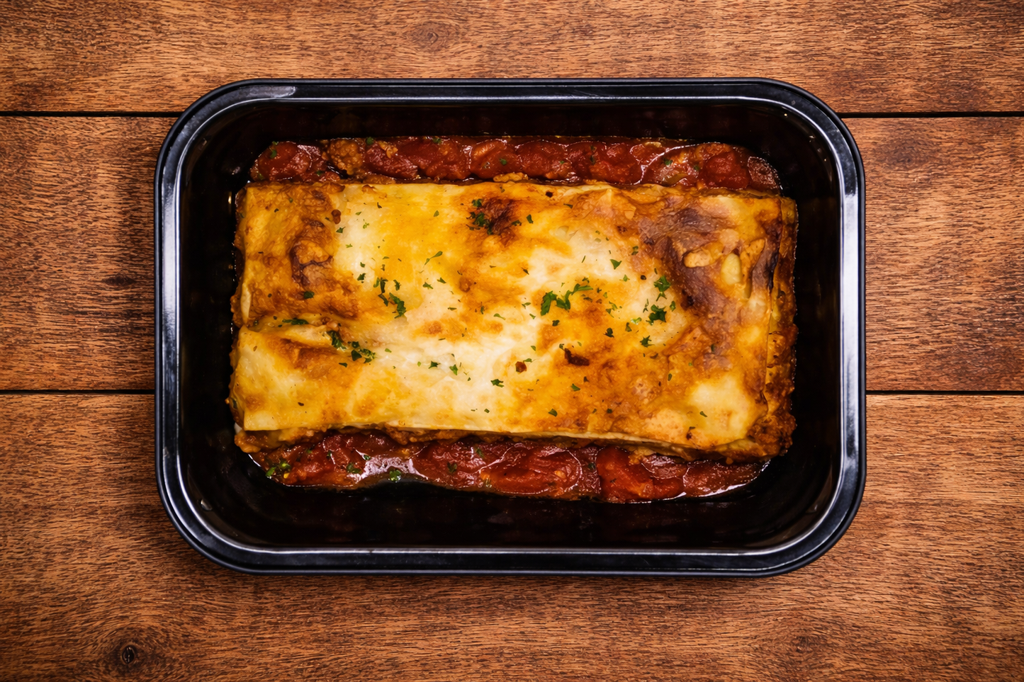 Frozen beef lasagna meal in tray, layered with beef mince, tomato sauce, and melted cheese