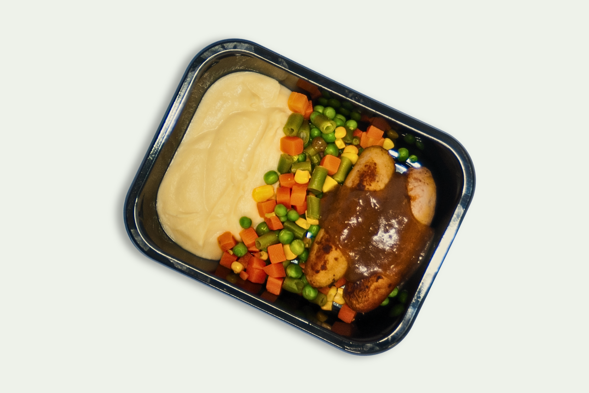Frozen pork sausages with mashed potatoes, steamed vegetables, and onion gravy